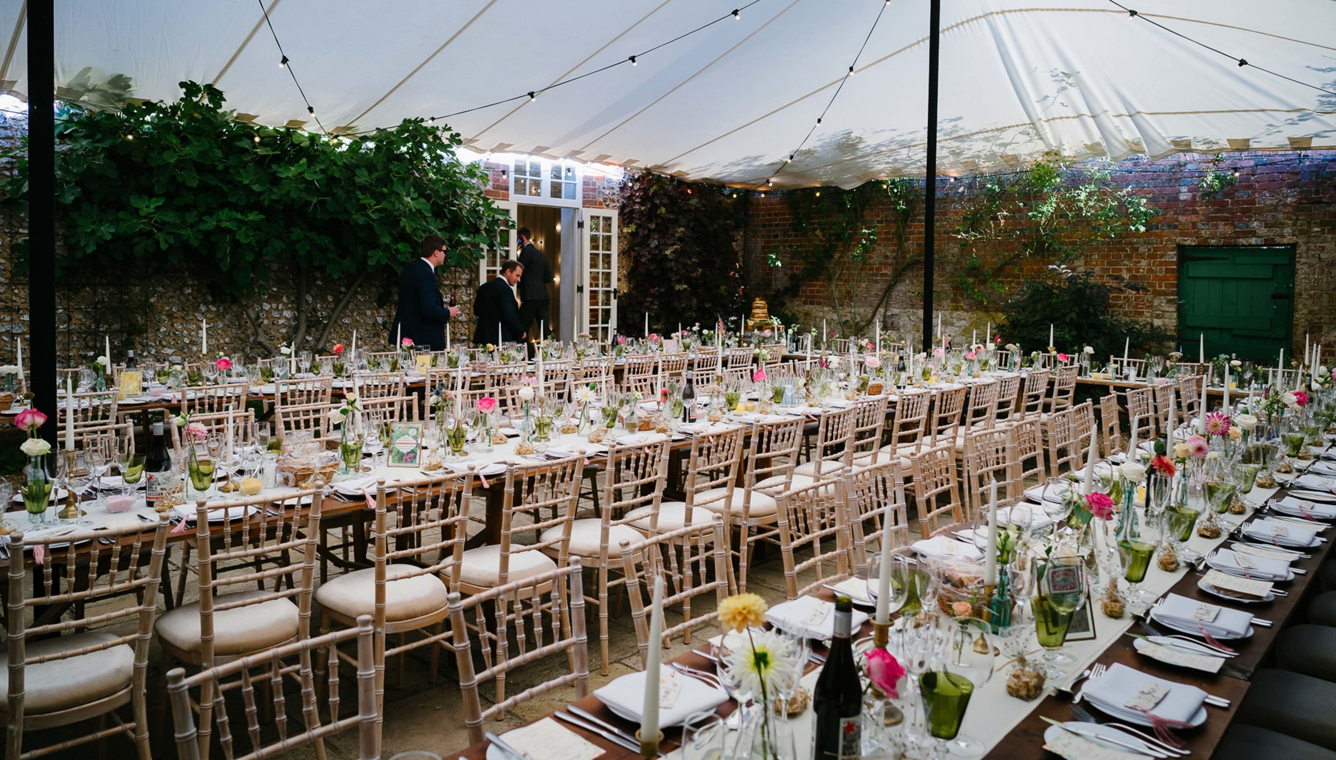 Bignor Park weddings courtyard reception tables and white chairs set up with overhead canvas