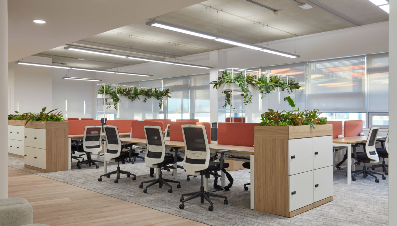 Modern open-plan office with ergonomic chairs, planter dividers, and natural lighting, part of the Idea Space workplace fit-out.