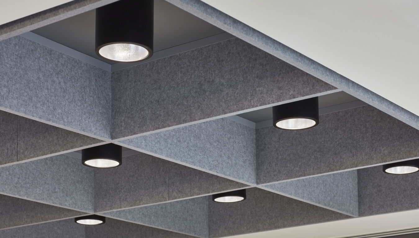 Ceiling grid features recessed cylindrical lights, glowing softly within a structured grey felt acoustic panel design.