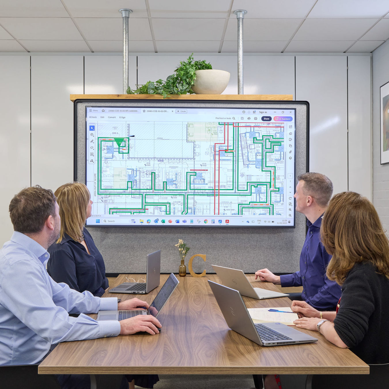 brightly lit, modern office with rows of empty desks, ergonomic chairs, and large windows