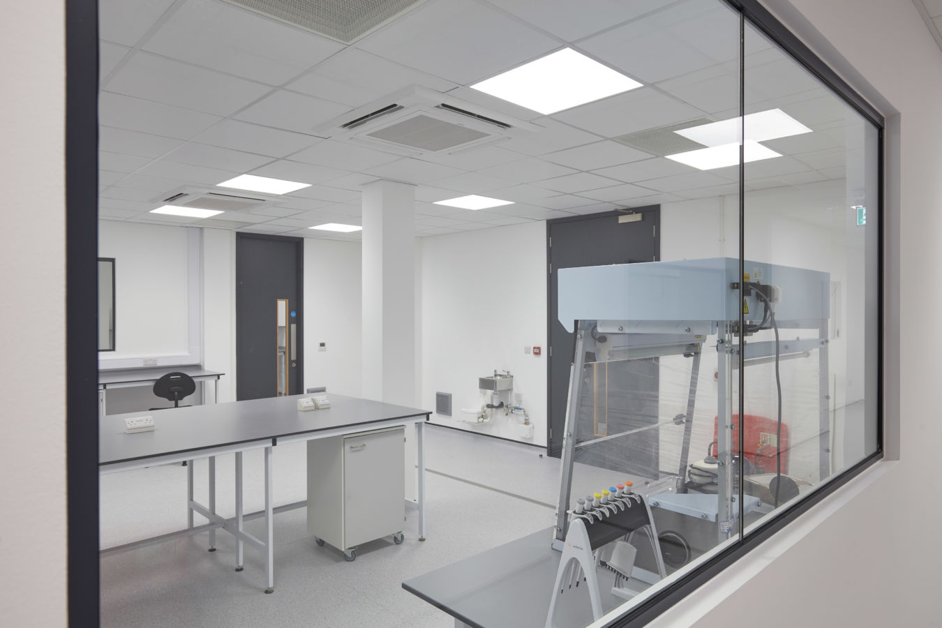 View through glass partition into a laboratory with workstations and specialised equipment, part of a COEL lab fit-out for Sense Bio.