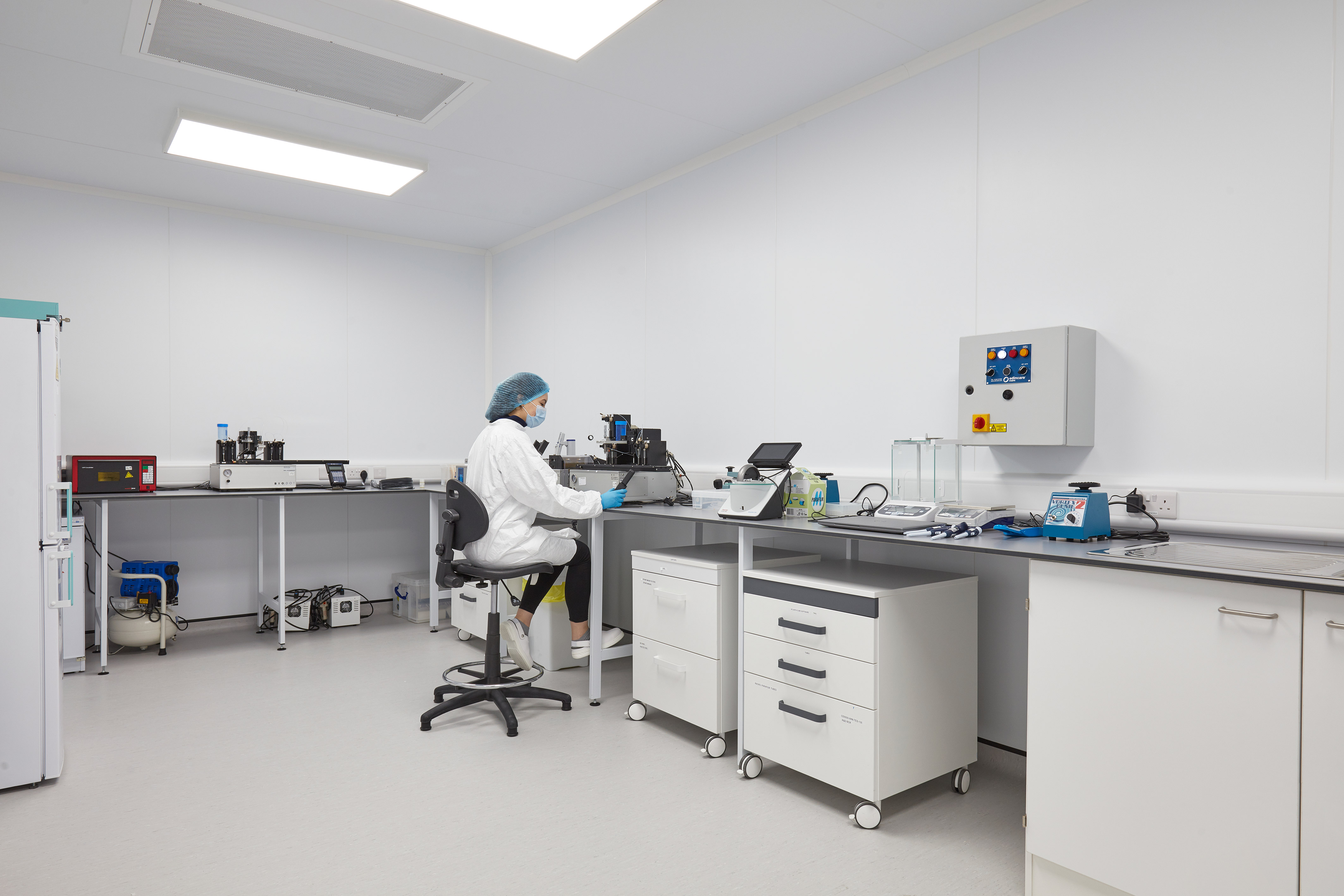 Scientist working in a clean, white laboratory equipped with workbenches and analytical instruments, part of a COEL lab fit-out for Sense Bio.