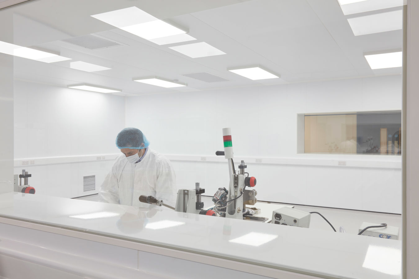 Laboratory technician working in a cleanroom environment with sterile white surfaces and equipment, part of a COEL Lab Planning project for Sense Bio.