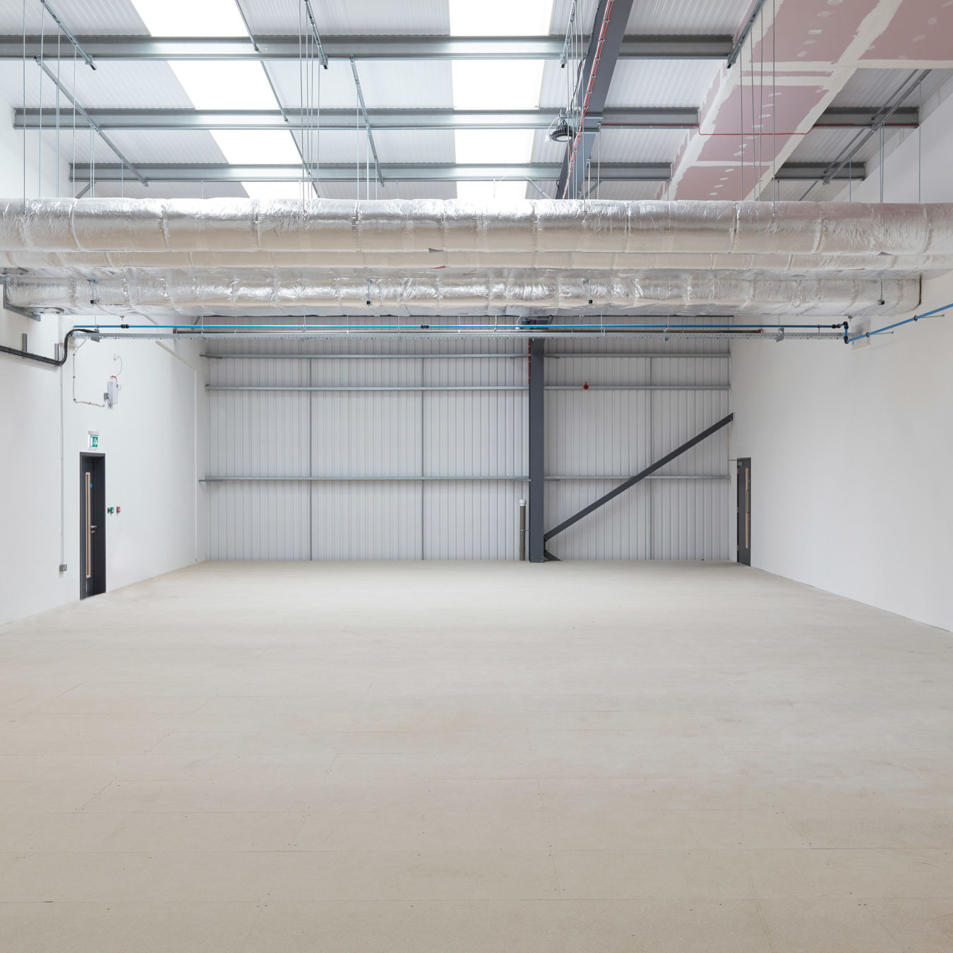 Empty industrial space with exposed ceiling ductwork and roller door, prepared for laboratory fit-out by COEL for Sense Bio.