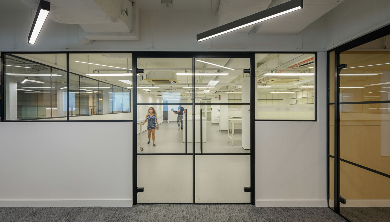 Modern office interior with black-framed glass partitions and visible laboratory space beyond, part of a COEL fit-out for Wren Therapeutics.