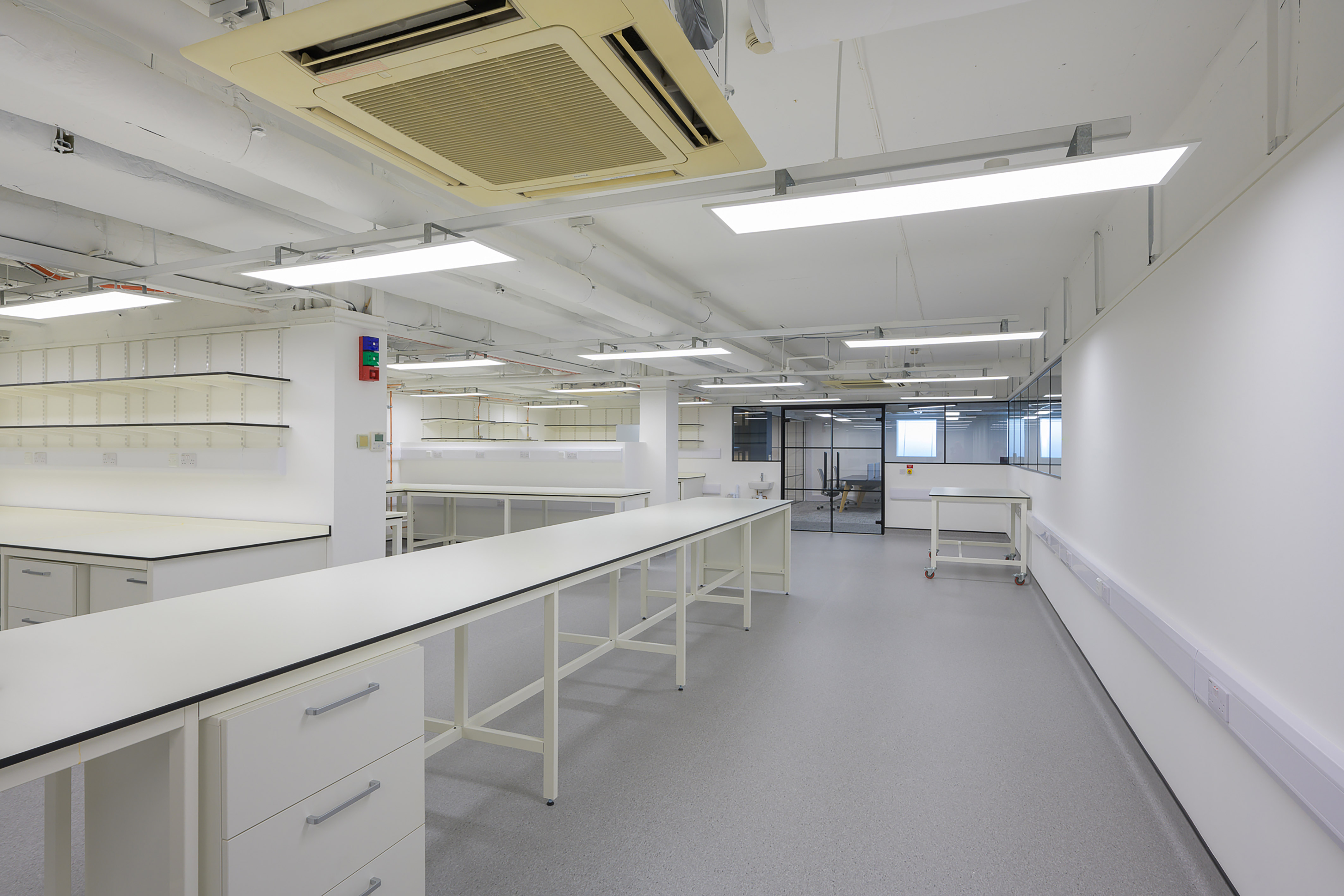 Spacious white laboratory interior with long workbenches, shelving, and overhead lighting, part of a COEL Lab Planning project for Wren Therapeutics.