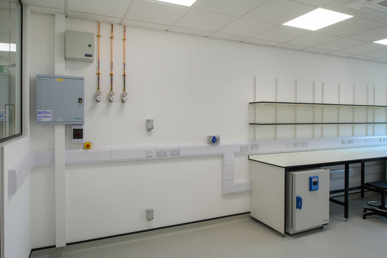 Clean and functional laboratory space with fitted workbenches, wall-mounted shelves, and utility connections, delivered by COEL for Transition Bio.