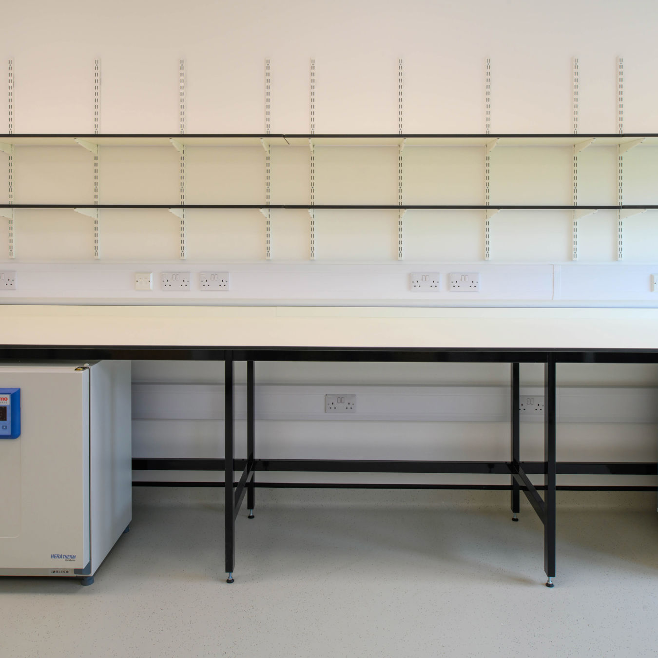 Laboratory workstation with shelving, integrated power outlets, and under-bench storage, designed by COEL for Transition Bio.