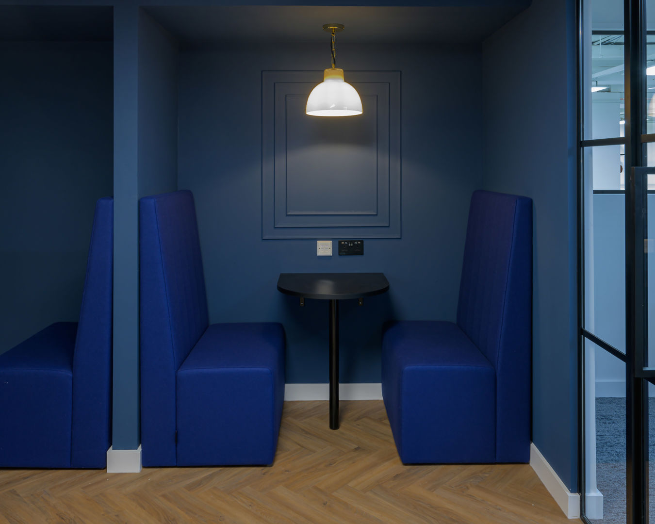 Blue co-working booth with a table and a light