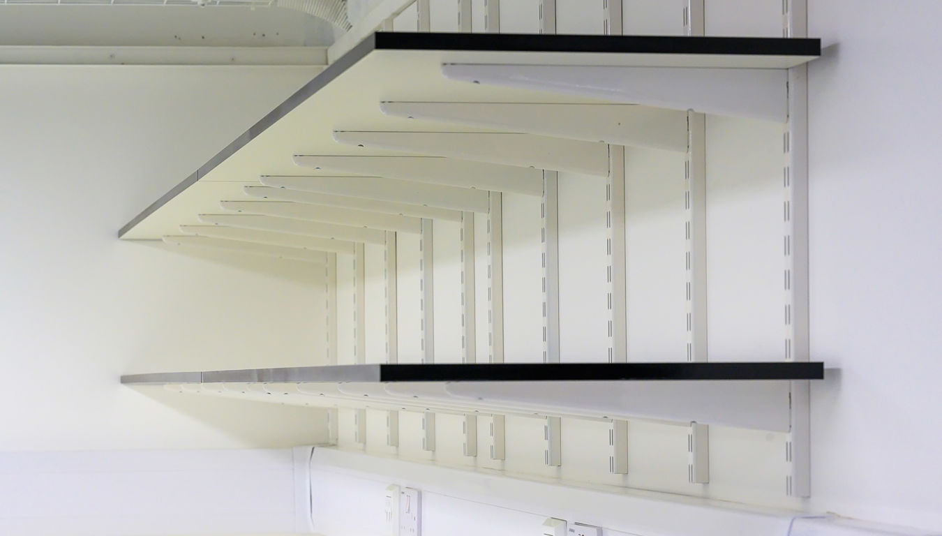 Wall-mounted laboratory shelving system with integrated power outlets, part of a COEL Lab Design project for Wren Therapeutics.