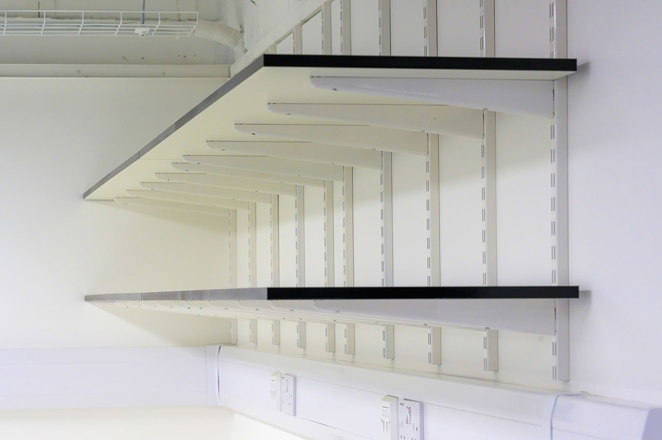 Wall-mounted laboratory shelving system with integrated power outlets, part of a COEL Lab Design project for Wren Therapeutics.