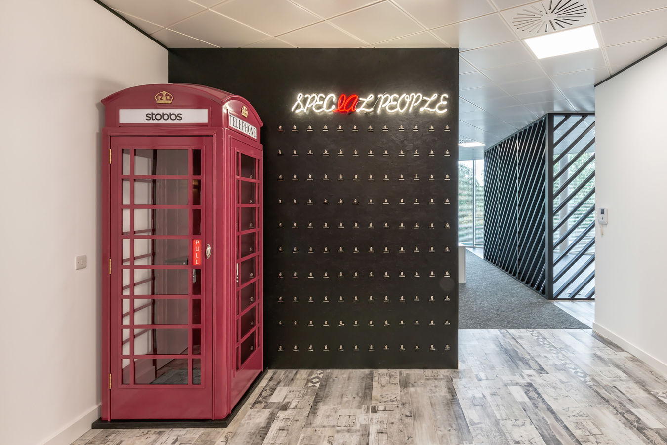 Office hallway featuring a red British-style phone booth repurposed as a private call space, part of a COEL fit-out for Stobbs.