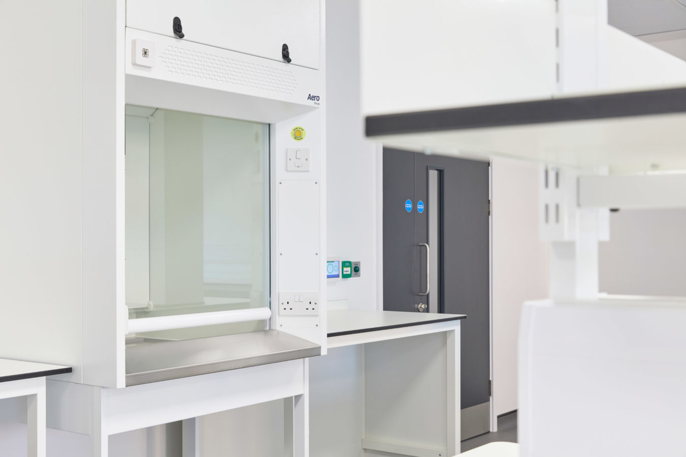 pristine, modern laboratory features a white fume hood and sleek gray cabinets. The atmosphere is clean and organized, conveying efficiency and precision