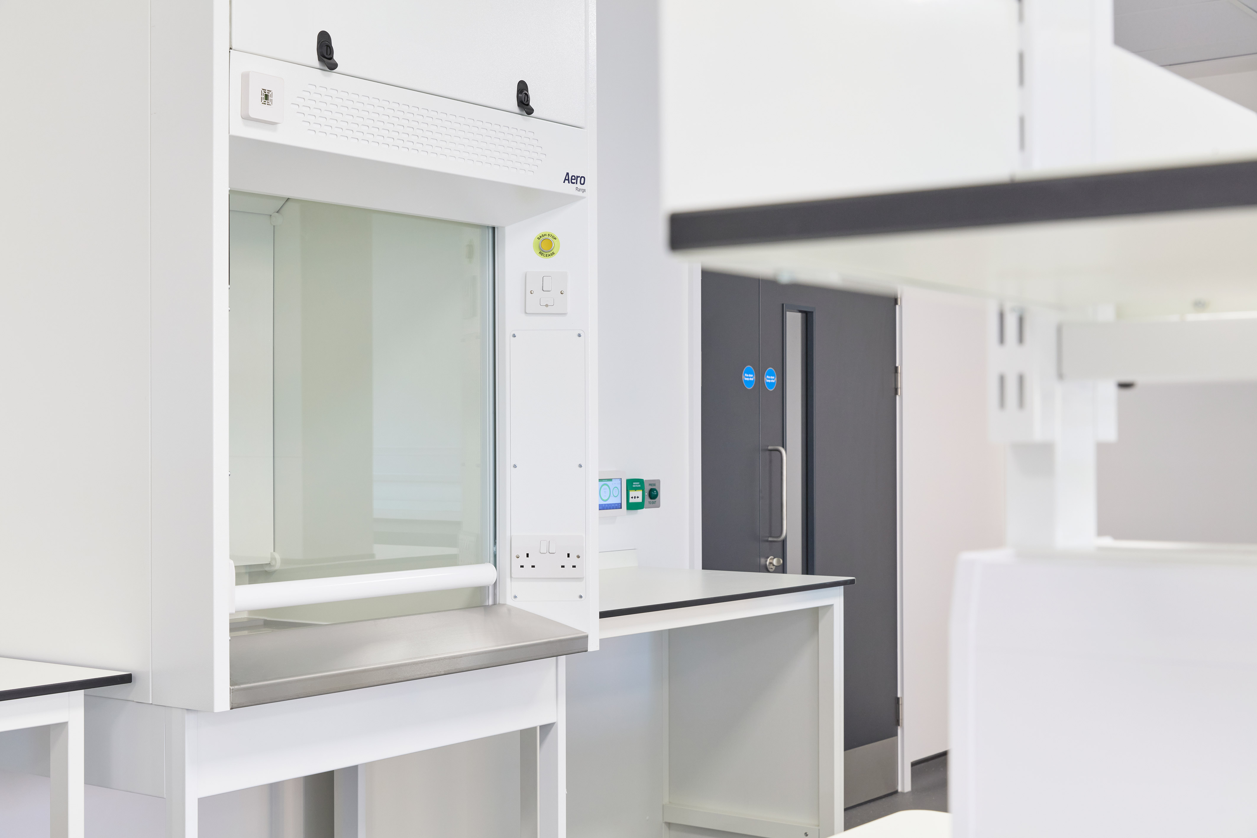 pristine, modern laboratory features a white fume hood and sleek gray cabinets. The atmosphere is clean and organized, conveying efficiency and precision