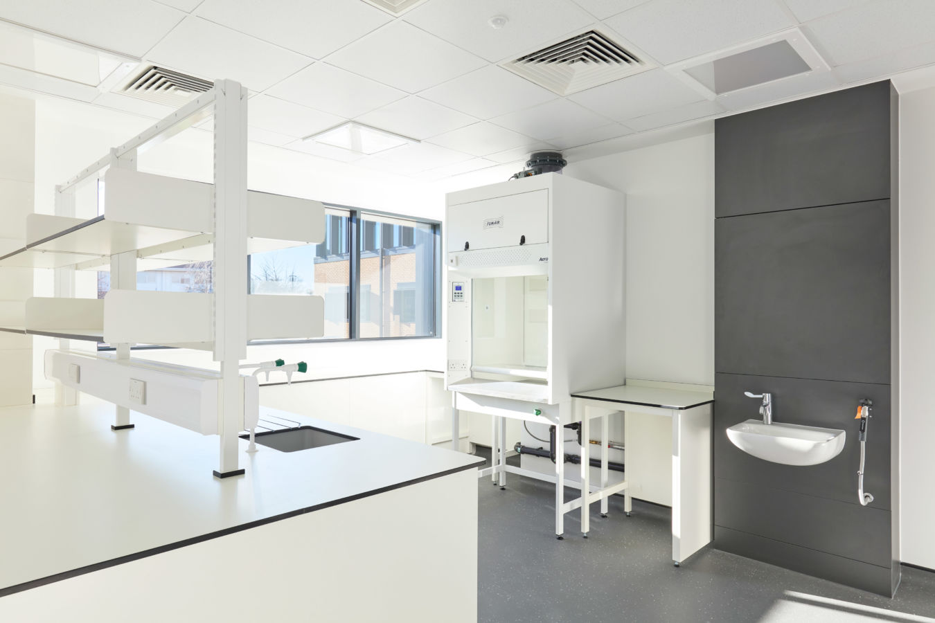 clean, well-lit laboratory with white and gray furniture and a sink