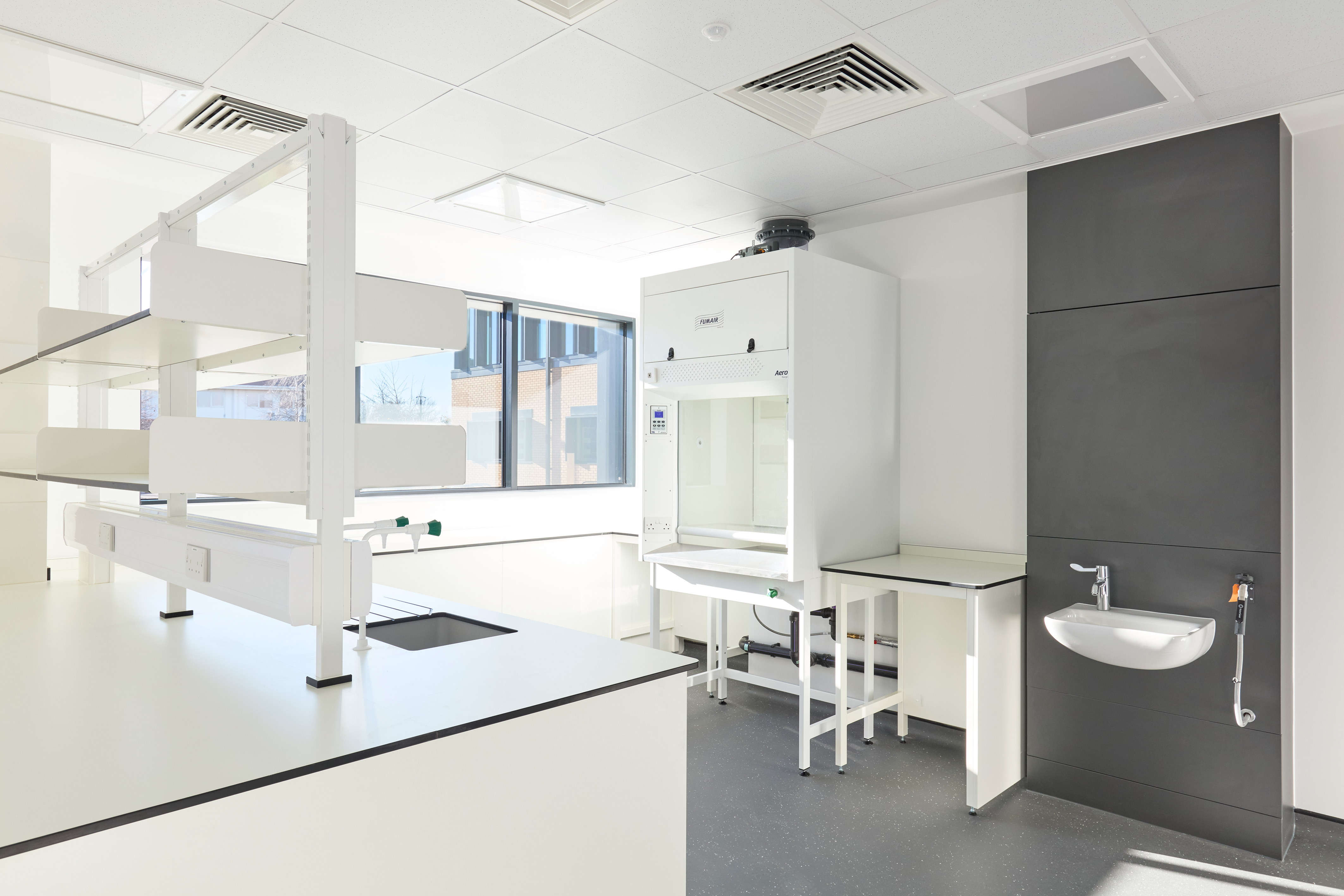 clean, well-lit laboratory with white and gray furniture and a sink