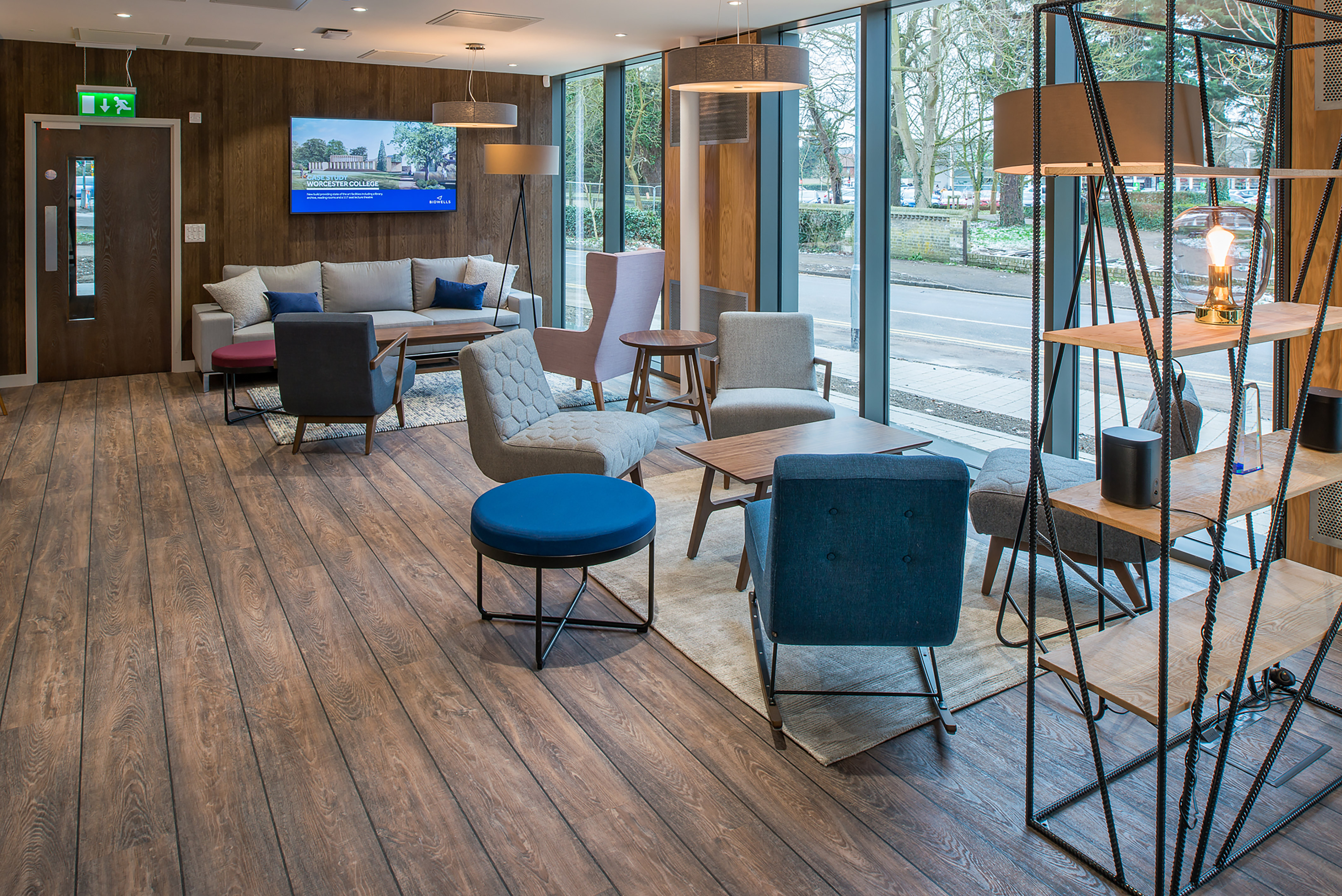 Contemporary office lounge with mixed seating, wood flooring, and natural light, furnished and styled by COEL.