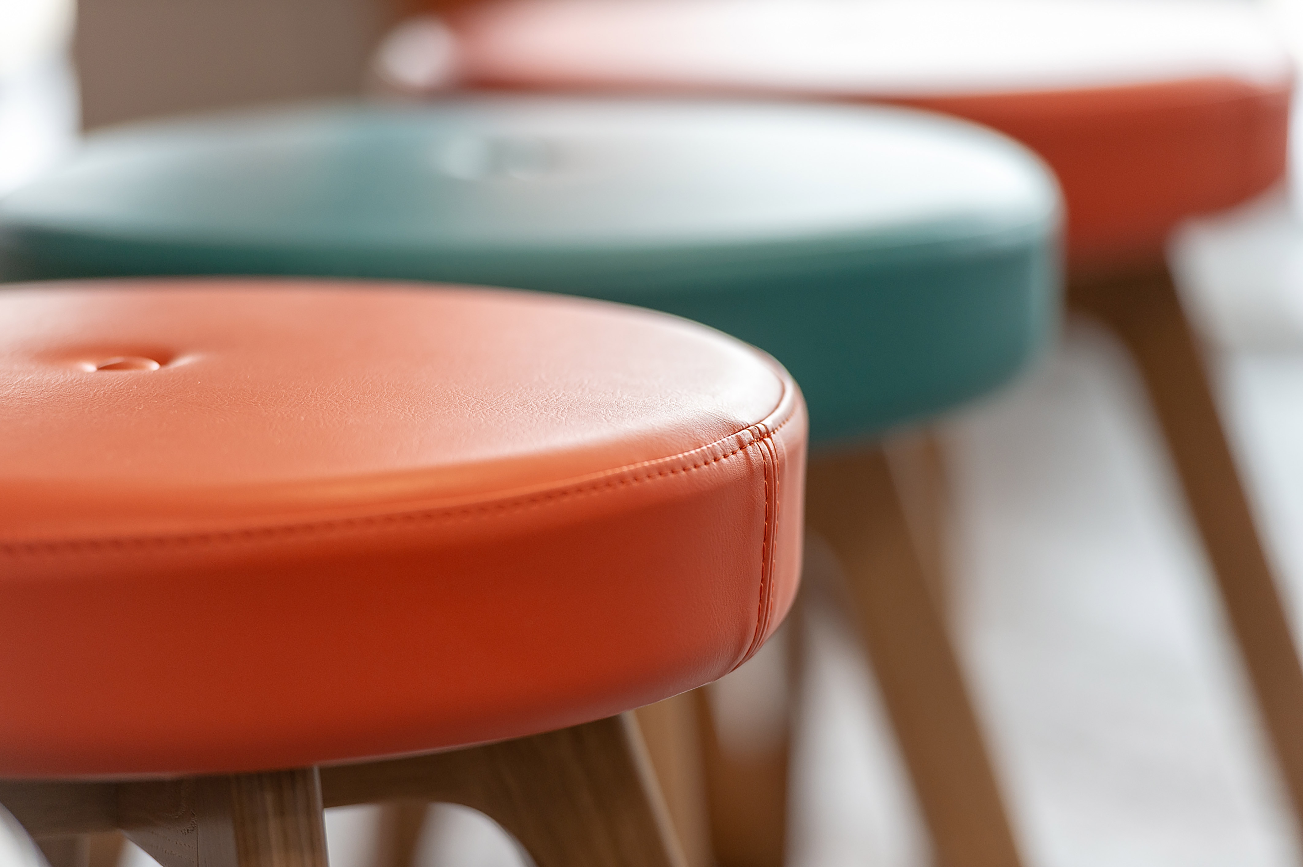 Close-up of colourful upholstered stools with wooden legs, part of a COEL office furniture installation for Birketts in Ipswich.