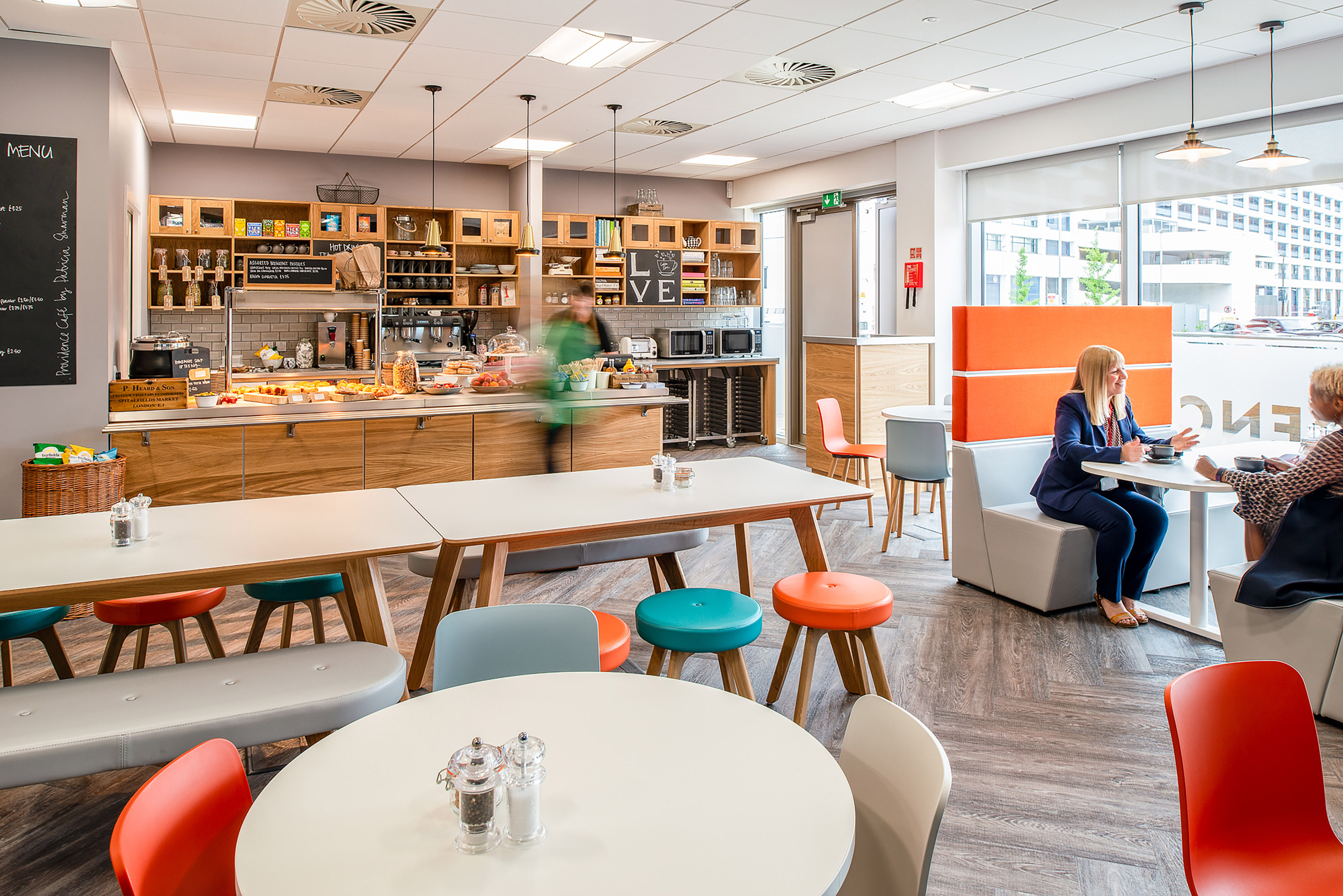bustling cafe with a long counter, diverse seating, and two women conversing at a booth