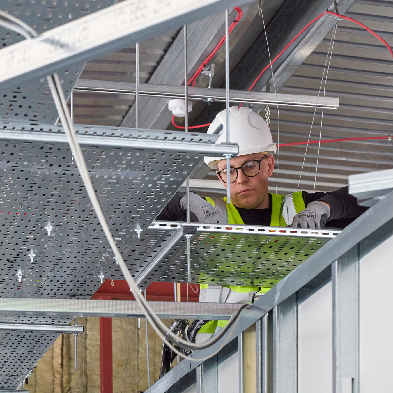 COEL site engineer working on ceiling infrastructure during laboratory fit-out, part of a lab design project in progress.