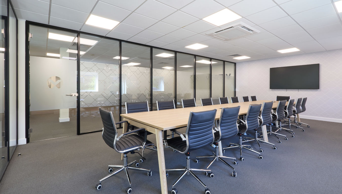 modern office meeting room with a long table, black chairs, and a large screen on the wall