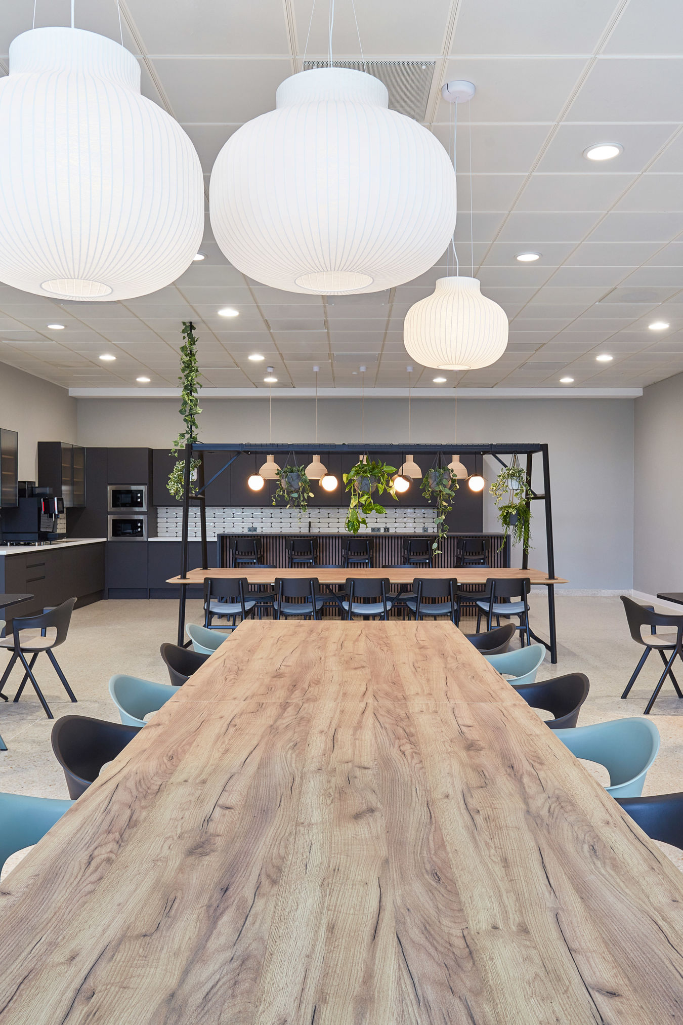 modern office break room with various seating areas, including a long wooden table and booths