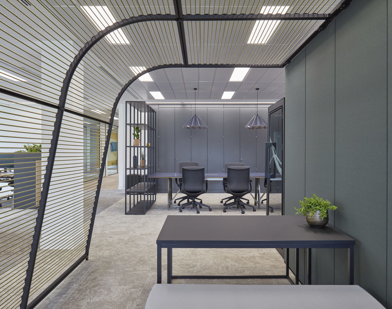modern office nook with a curved slat wall, a small table, and a glimpse into a private office space